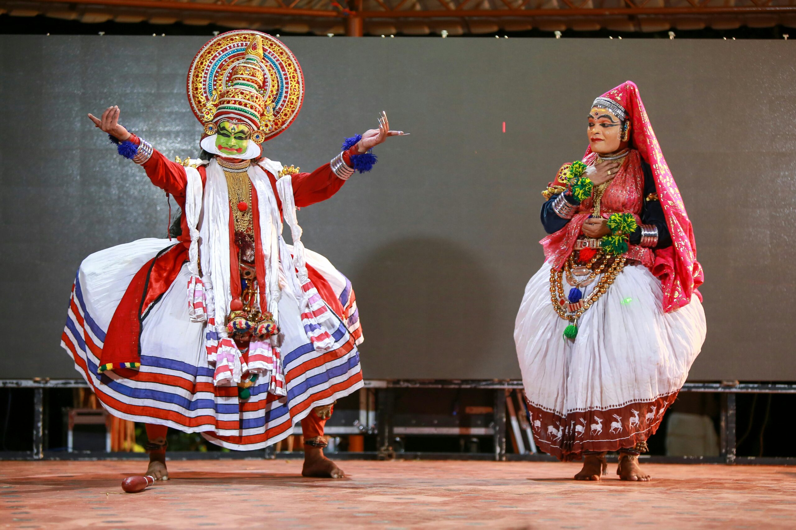 Vibrant Kathakali dancers performing in traditional costumes at a cultural event in Kerala, India.